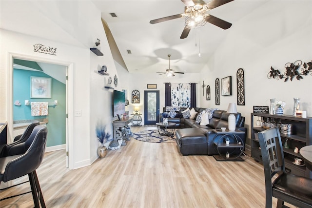 living area with high vaulted ceiling, visible vents, baseboards, and wood finished floors