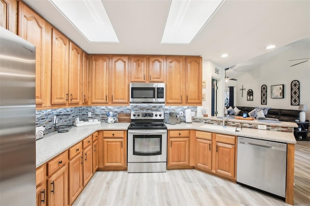 kitchen featuring a skylight, stainless steel appliances, open floor plan, a sink, and ceiling fan