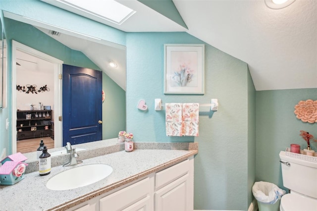 half bathroom featuring toilet, lofted ceiling with skylight, visible vents, and vanity