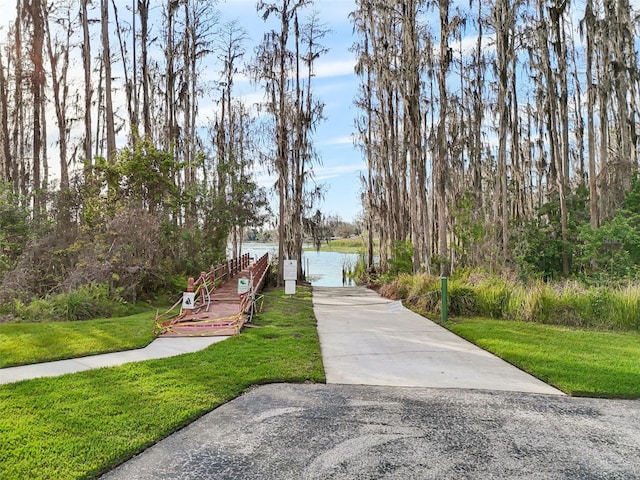 surrounding community featuring a garage, a lawn, and a water view