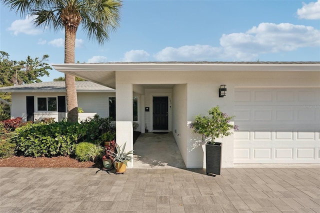 entrance to property with a garage and stucco siding