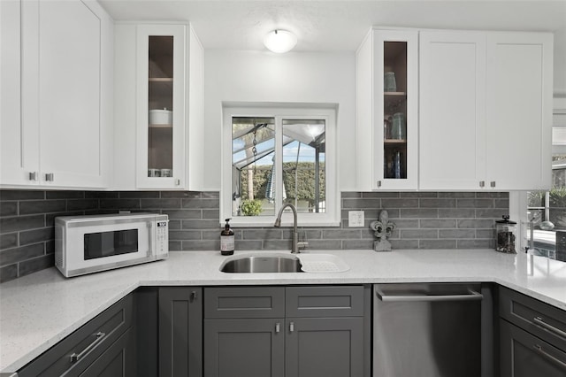 kitchen featuring gray cabinets, white microwave, white cabinets, a sink, and dishwasher