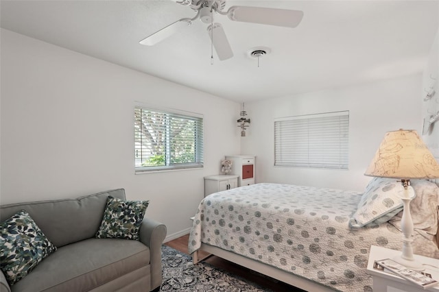 bedroom with a ceiling fan, baseboards, visible vents, and wood finished floors