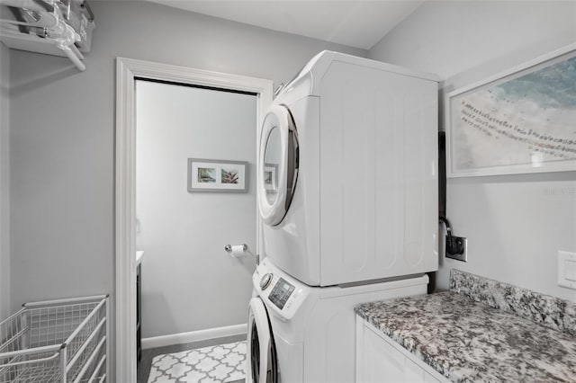 laundry room with laundry area, baseboards, and stacked washer and dryer