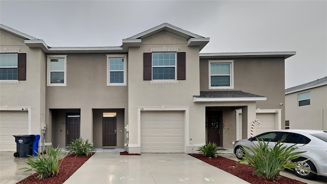 multi unit property featuring an attached garage, concrete driveway, and stucco siding