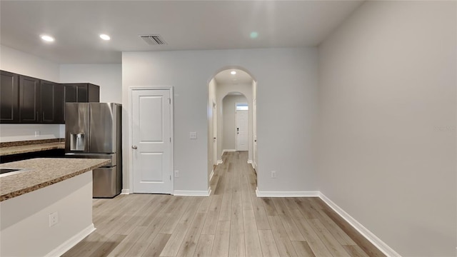 kitchen featuring stainless steel fridge, visible vents, arched walkways, baseboards, and light wood-style flooring