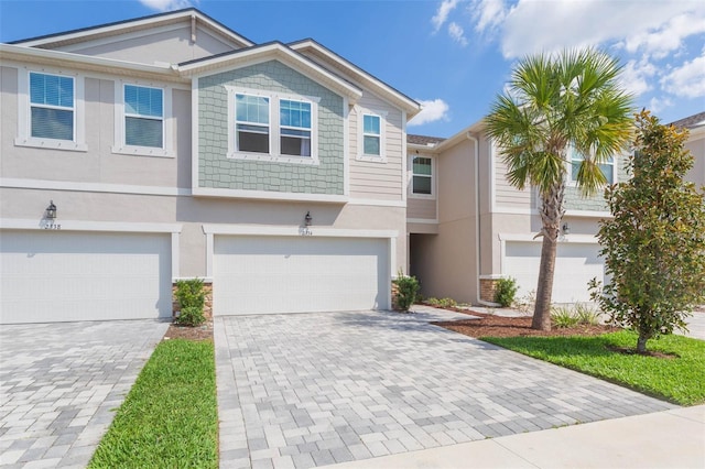 townhome / multi-family property featuring decorative driveway, an attached garage, and stucco siding