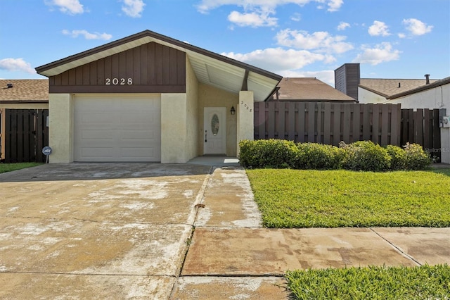 view of front of property featuring an attached garage, fence, concrete driveway, and stucco siding