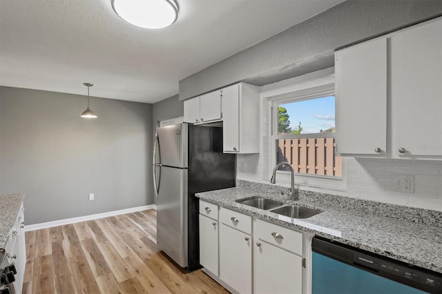 kitchen with light wood-style flooring, freestanding refrigerator, white cabinetry, a sink, and dishwashing machine