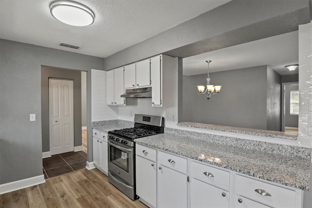 kitchen featuring stainless steel gas range oven, visible vents, wood finished floors, under cabinet range hood, and white cabinetry