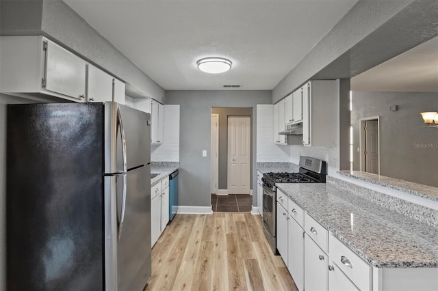 kitchen featuring light wood-style flooring, under cabinet range hood, stainless steel appliances, visible vents, and white cabinets