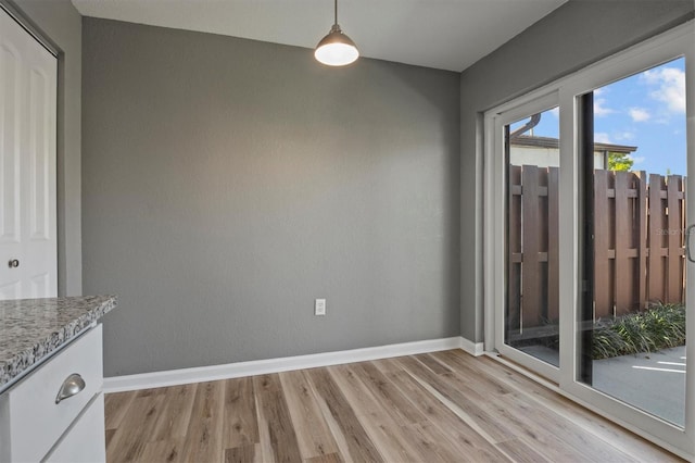 unfurnished dining area with light wood finished floors and baseboards