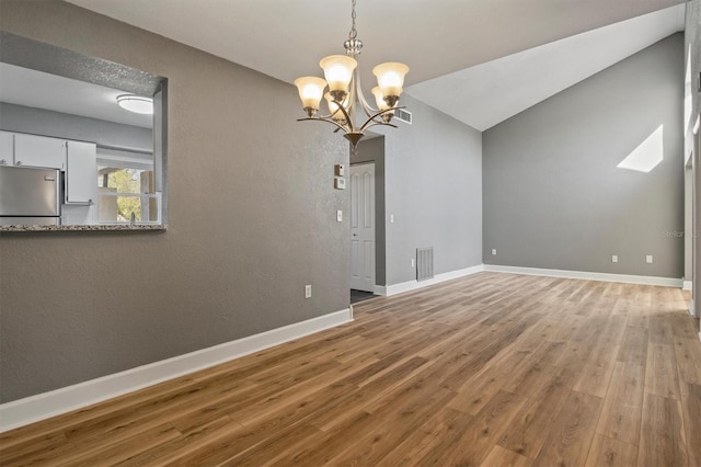 unfurnished room featuring lofted ceiling, visible vents, baseboards, and wood finished floors