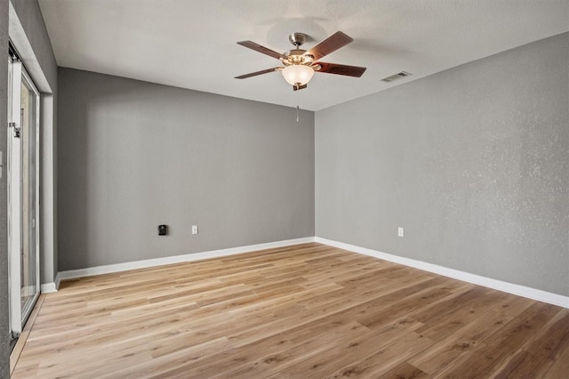 empty room with a ceiling fan, light wood-type flooring, visible vents, and baseboards