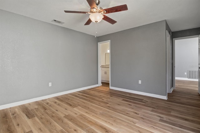 unfurnished bedroom featuring light wood finished floors, baseboards, visible vents, and ensuite bathroom