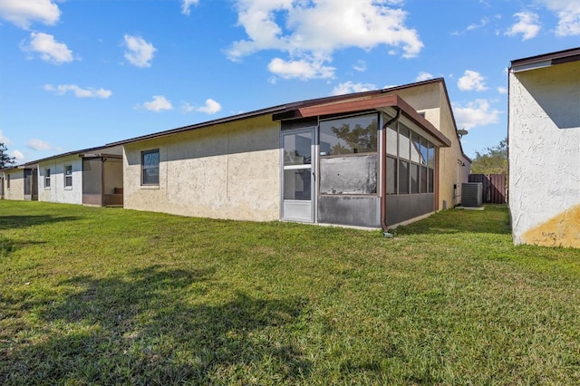 back of house featuring a yard, a sunroom, and central air condition unit