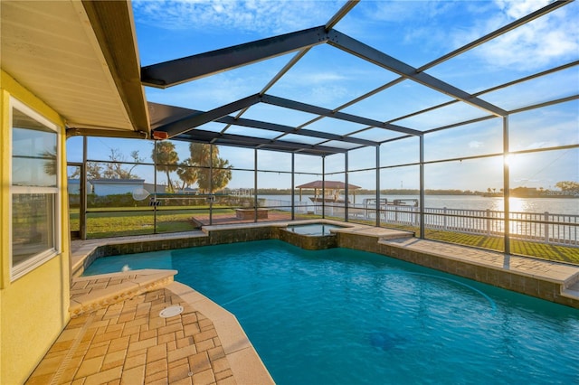 view of pool featuring a pool with connected hot tub, glass enclosure, a patio area, and a water view