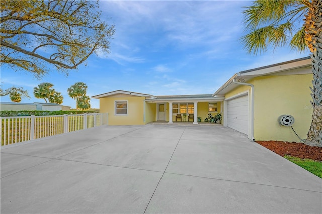 exterior space featuring an attached garage, fence, concrete driveway, and stucco siding