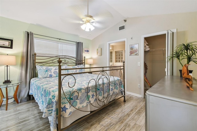 bedroom with visible vents, light wood-style floors, vaulted ceiling, a spacious closet, and a closet