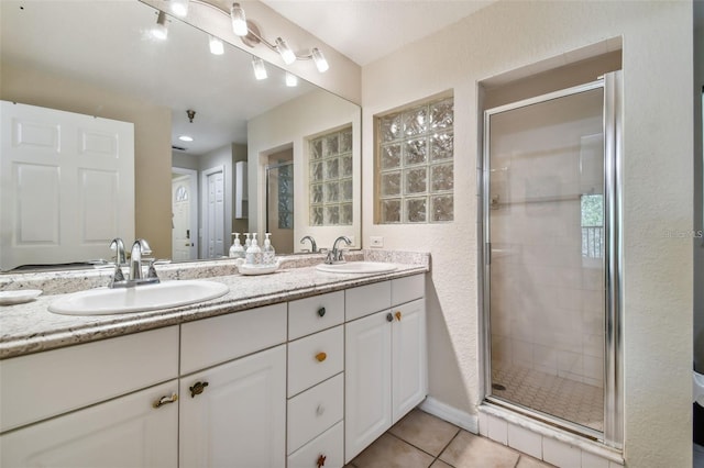 full bathroom featuring a stall shower, tile patterned flooring, a sink, and double vanity