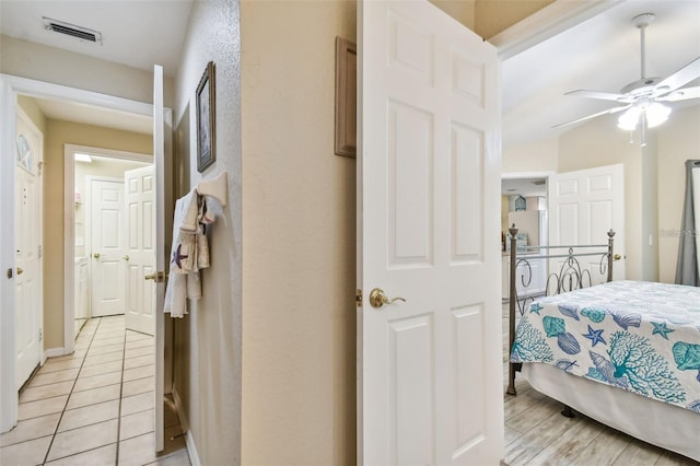 bedroom featuring light tile patterned floors, visible vents, and a ceiling fan