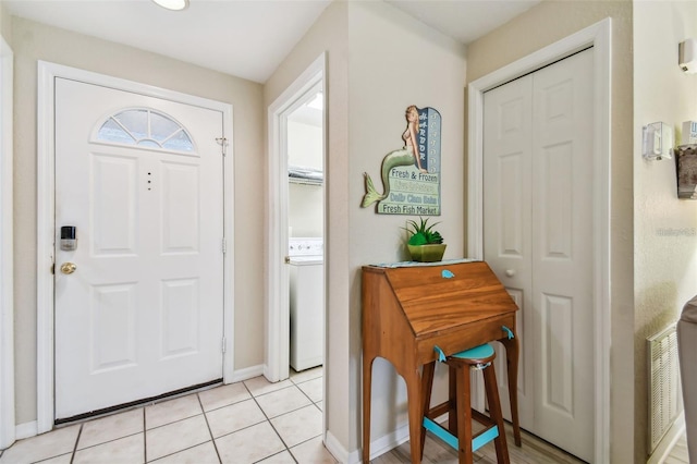 foyer entrance with light tile patterned floors, washer / dryer, and baseboards