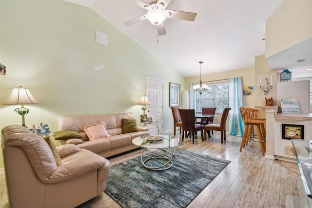 living area with ceiling fan with notable chandelier, high vaulted ceiling, baseboards, and light wood-style floors