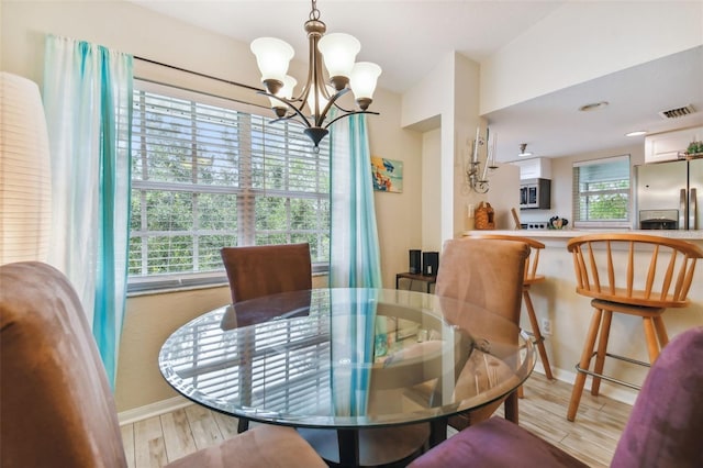 dining area with baseboards, a notable chandelier, visible vents, and wood finished floors