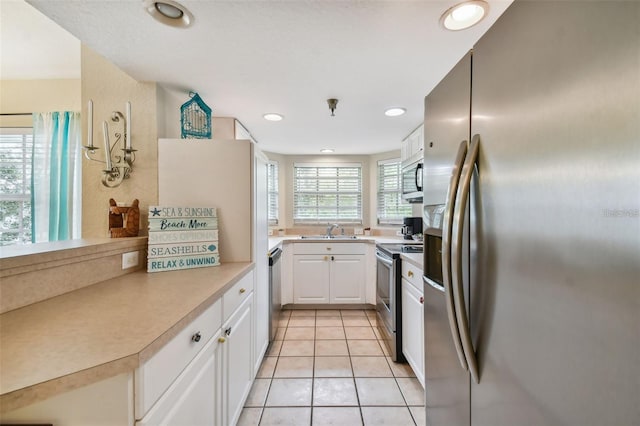 kitchen featuring stainless steel appliances, light tile patterned flooring, a sink, and a wealth of natural light