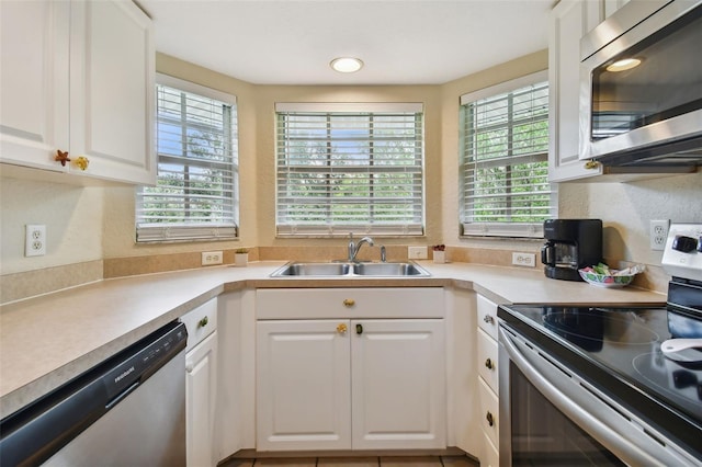 kitchen with light countertops, appliances with stainless steel finishes, a sink, and white cabinets