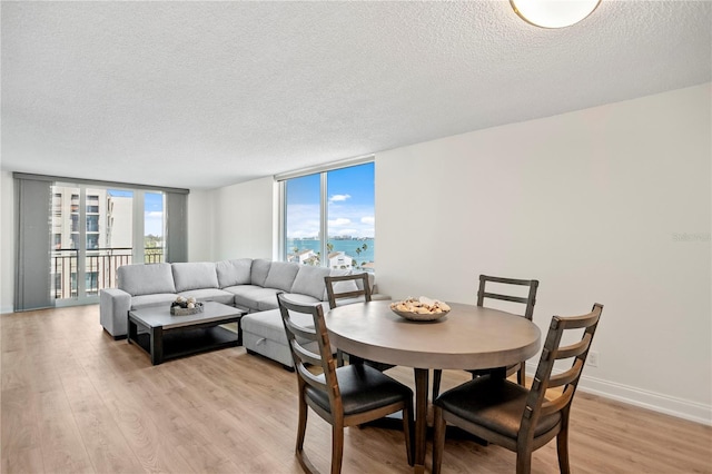 dining space with plenty of natural light, light wood-type flooring, and floor to ceiling windows