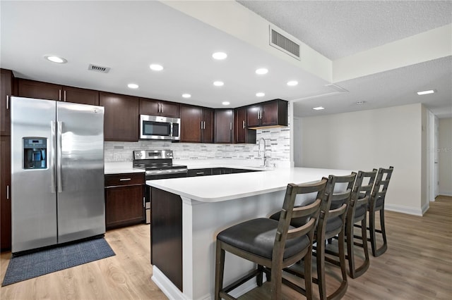 kitchen with appliances with stainless steel finishes, light countertops, visible vents, and light wood-style floors