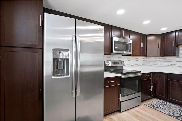 kitchen featuring stainless steel appliances, light countertops, light wood-style flooring, decorative backsplash, and dark brown cabinetry