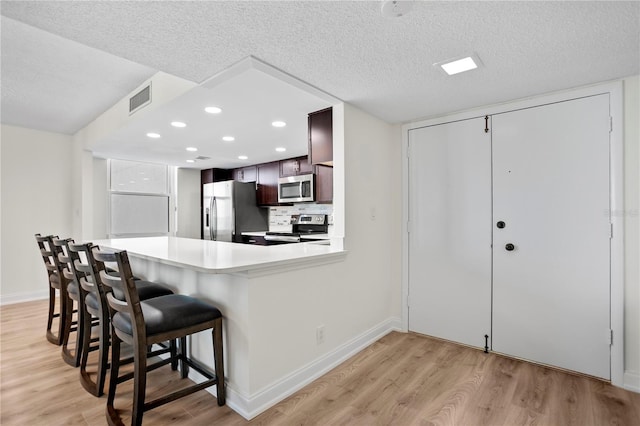 kitchen featuring light countertops, appliances with stainless steel finishes, light wood-style flooring, and visible vents