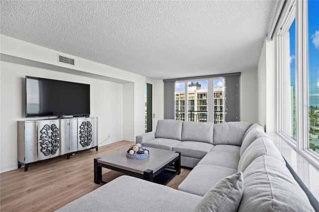 living room with plenty of natural light, a textured ceiling, visible vents, and wood finished floors