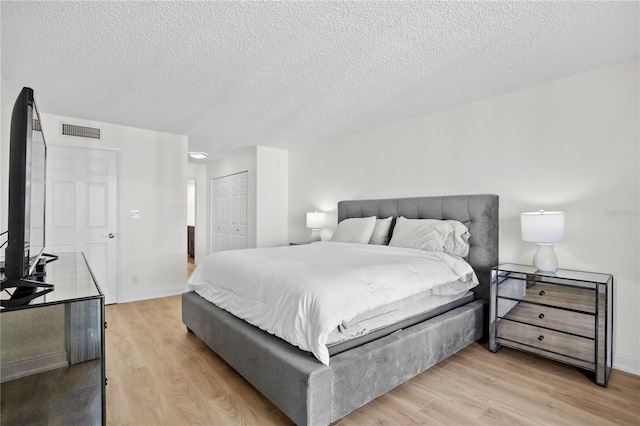 bedroom with light wood-style flooring, a closet, visible vents, and baseboards