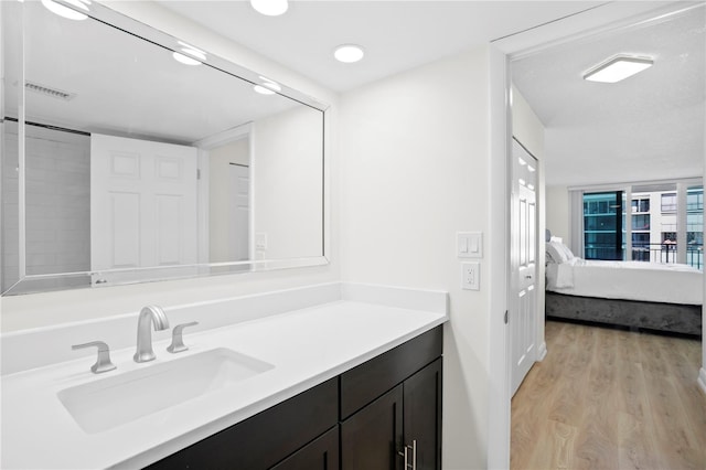 ensuite bathroom with ensuite bathroom, vanity, wood finished floors, and visible vents