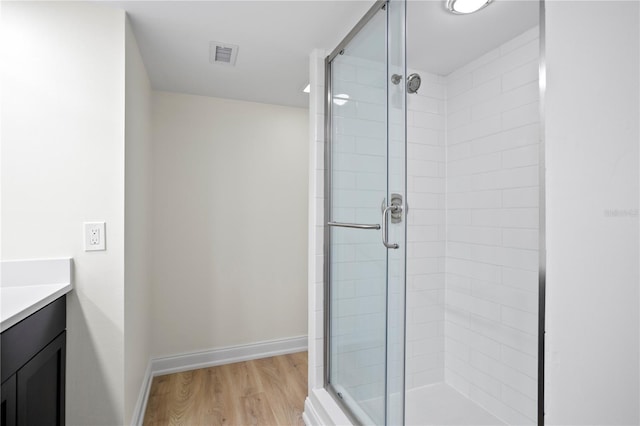 bathroom featuring a stall shower, baseboards, visible vents, wood finished floors, and vanity