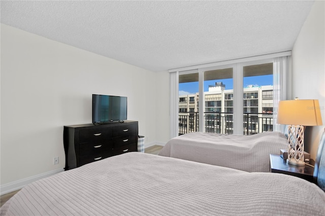 bedroom featuring access to exterior, baseboards, and a textured ceiling