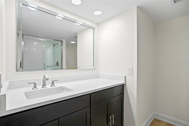 full bathroom featuring a stall shower, wood finished floors, vanity, and baseboards