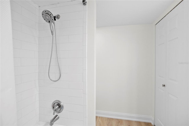 full bath featuring  shower combination, baseboards, and wood finished floors