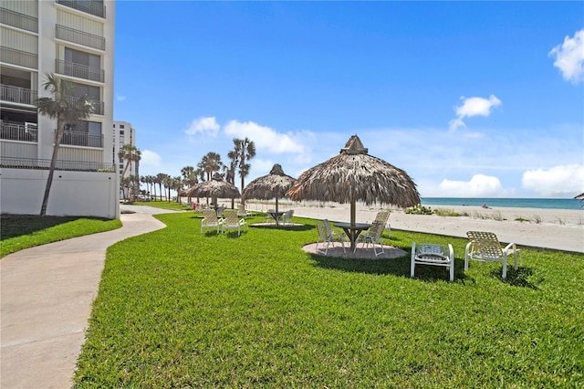 view of home's community with a yard, a beach view, a water view, and a gazebo