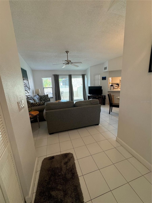 living area with light tile patterned floors, baseboards, and a textured ceiling