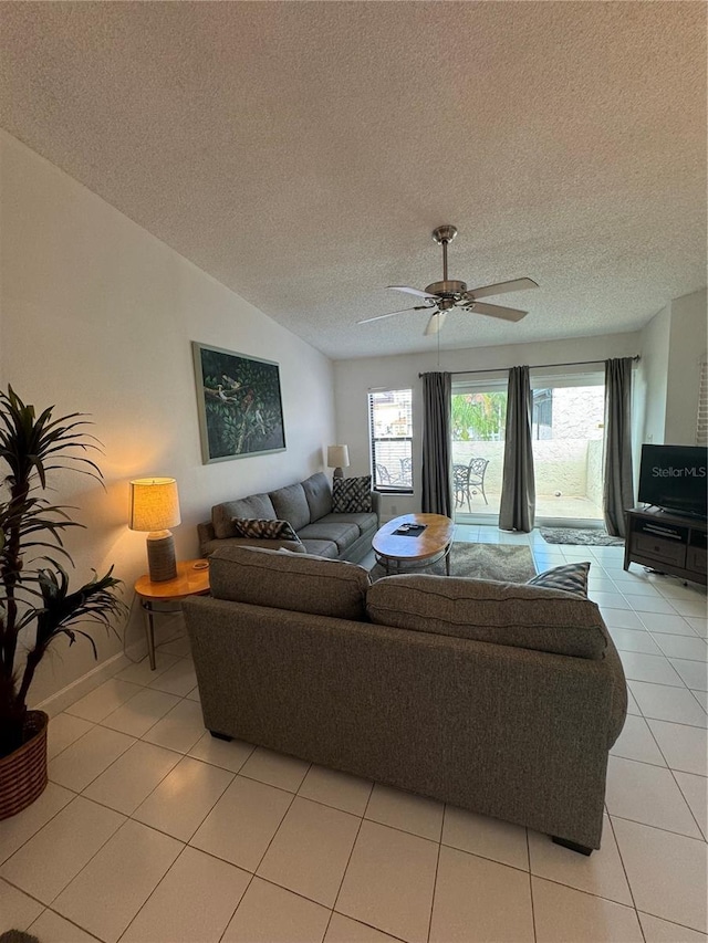 living room featuring light tile patterned floors, ceiling fan, a textured ceiling, and baseboards