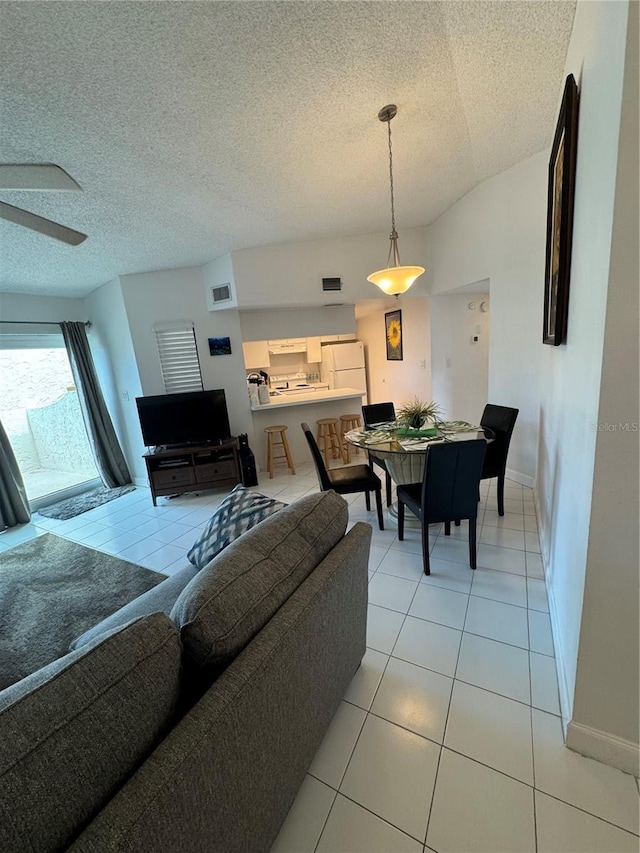 living room featuring light tile patterned floors, ceiling fan, a textured ceiling, and lofted ceiling