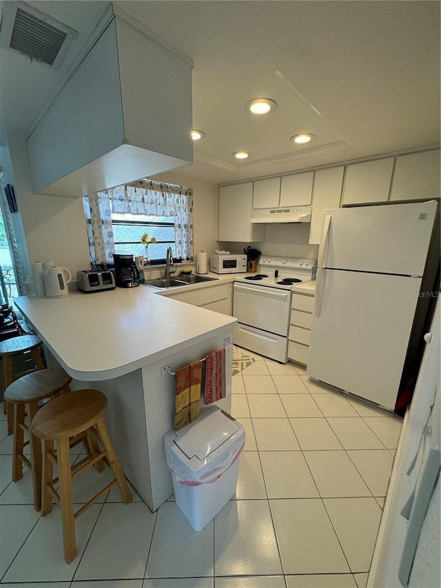 kitchen with under cabinet range hood, a peninsula, white appliances, a sink, and visible vents