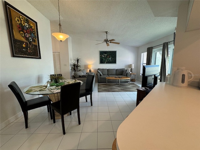 dining room with ceiling fan, a textured ceiling, light tile patterned flooring, baseboards, and vaulted ceiling