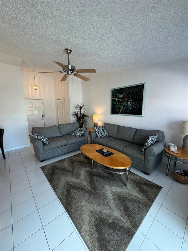 living area featuring ceiling fan, a textured ceiling, and light tile patterned floors