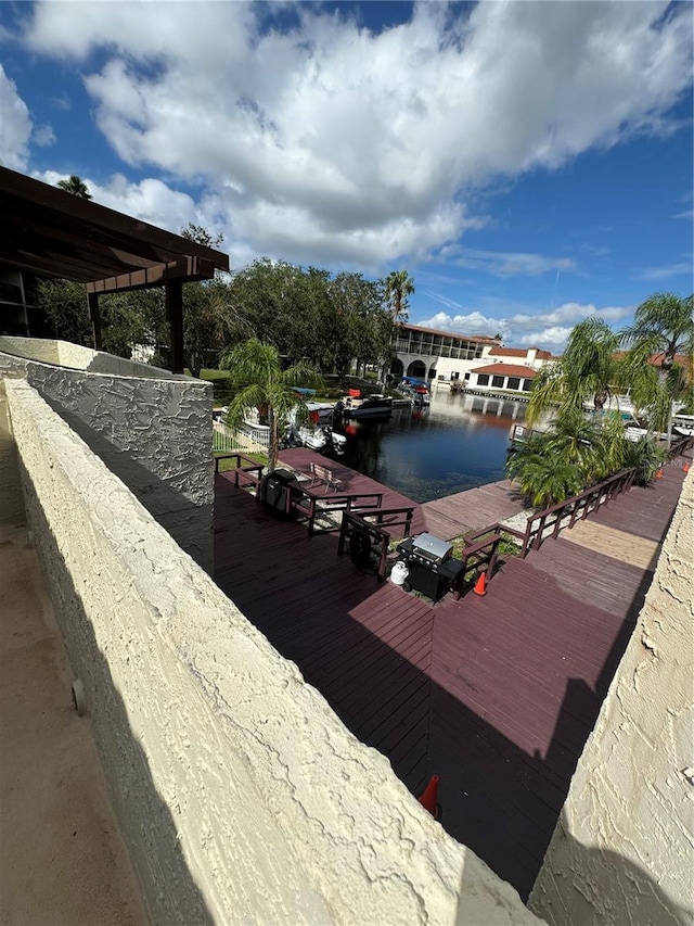 wooden terrace with a water view and a boat dock