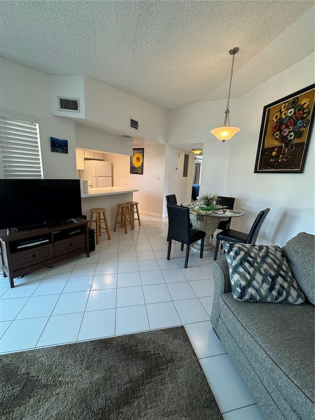 living area featuring light tile patterned floors, a textured ceiling, and visible vents